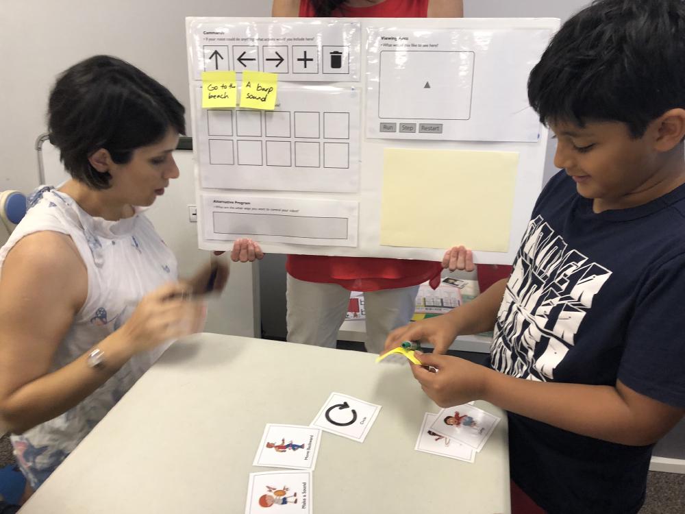 A camper adds sticky notes to a design board with his ideas.